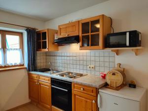 a small kitchen with wooden cabinets and a black dishwasher at Schmidtler`s Nest in Warngau