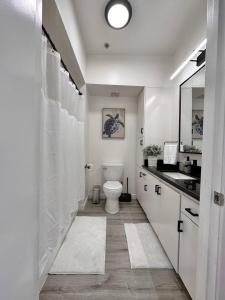 Baño blanco con aseo y lavamanos en Luxurious Condo Walking Distance to San Diego Bay! en San Diego