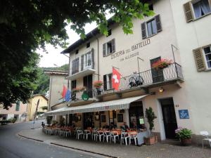 un restaurante con mesas y sillas frente a un edificio en Osteria Battello, en Caslano