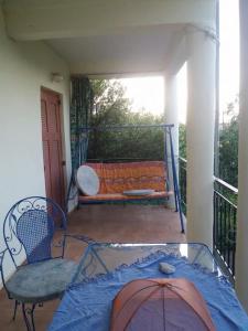 un balcón con una mesa de cristal y un banco en un porche en Ideal Cottage Holidays-Ιδανικές Εξοχικές Διακοπές, en Áyioi Apóstoloi