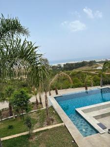 a swimming pool with palm trees and the ocean at Villa Marina Hills - Tamuda Bay in Jebel Zemzem