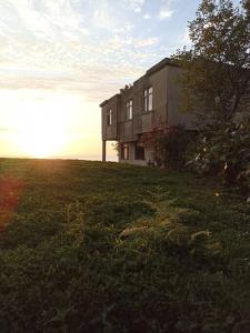 una casa en una colina de hierba con la puesta de sol detrás de ella en Deniz ve Doğa Manzaralı, en Fındıklı