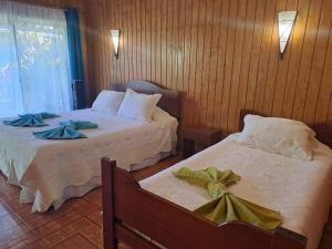 two beds in a hotel room with bows on them at Hostal Avareipua in Hanga Roa