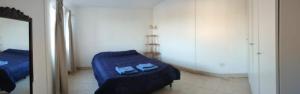 1 dormitorio con cama azul y espejo en Departamento con iluminación natural y ambientes confortables, en una ubicación privilegiada. en Godoy Cruz