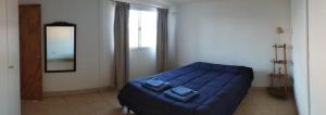 1 dormitorio con cama azul y espejo en Departamento con iluminación natural y ambientes confortables, en una ubicación privilegiada. en Godoy Cruz