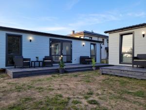 a manufactured home with a deck with furniture on it at "AGUŚ" Komfortowe i nowczesne domki w cichej okolicy niedaleko plaży in Ostrowo