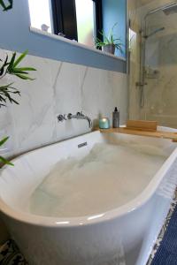 a white bath tub in a bathroom with a mirror at Farways Den in Haworth