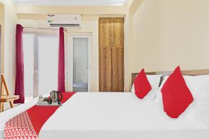 een slaapkamer met een groot wit bed met rode kussens bij OYO Star Residency Near Omaxe Gurgaon Mall in Gurgaon