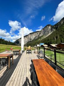 a wooden deck with tables and chairs and mountains at Hameau des Prodains - Résidence in Morzine