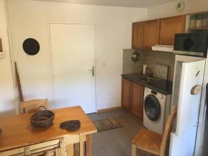 a kitchen with a table and a white refrigerator at Logement au pied des pistes Superdevoluy in Le Dévoluy +3 photos