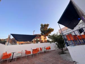 un patio con sillas naranjas, una mesa y una pared blanca en Blue Hotel boutique, en Selínia