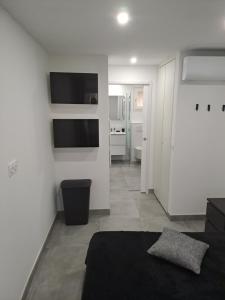 um quarto branco com uma cama e uma televisão na parede em Résidence Odalys Saint Loup Appartement Climatisé entierement rénové em Cap d'Agde