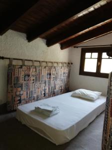 1 dormitorio con 1 cama con sábanas blancas y ventana en Villa Fanis, en Nea Epidavros