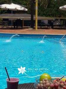 - une table avec un bol de fruits à côté de la piscine dans l'établissement Hotel Maitei Posadas, à Posadas