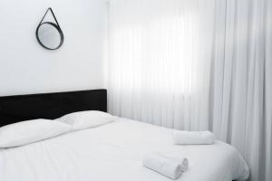 cama blanca con cabecero negro y espejo en אשראם 4 -דירת נופש עם חדר שינה וסלון במיקום מעולה, en Eilat