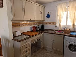 una cocina con armarios blancos y fregadero en Carolinas aptmt Orihuela, en Villacosta