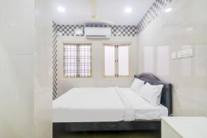 a white bedroom with a bed and a window at OYO Hotel Aroma Classic Near Nampally Railway station in Hyderabad