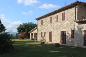 an old stone building in a grassy field at Agriturismo Il Poggiolo in Montemerano