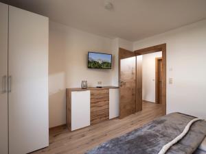 1 dormitorio con 1 cama y TV en la pared en Bergpanorama Kössen, en Kössen