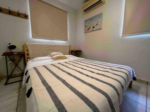 um quarto com uma cama com um cobertor listrado em Bella Casita Ayala- Zapata em Cabo Rojo