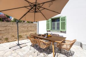 木洛希尼的住宿－Sidrina，庭院里配有一张带椅子和遮阳伞的木桌