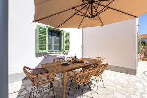 - une table en bois avec des chaises et un parasol sur la terrasse dans l'établissement Sidrina, à Mali Lošinj