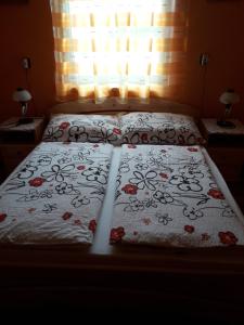 uma cama com uma colcha com flores em Kelemen Apartmanok em Abádszalók