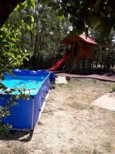 un parque infantil con una mesa azul y un tobogán rojo en Kelemen Apartmanok, en Abádszalók