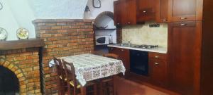 a kitchen with a table and a brick fireplace at Casa Cantina ad un passo dal mare in Santo Stefano al Mare