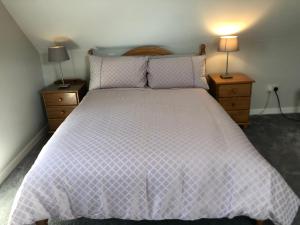 a bed with a white comforter and two lamps at Sióg in Oughterard