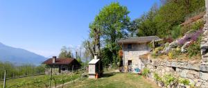a stone house with a small building on a hill at Agriturismo Ai Ronchi in Sorico