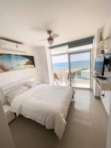 een slaapkamer met een bed en uitzicht op de oceaan bij Dpto frente al mar, piscina, check in automático in Playas