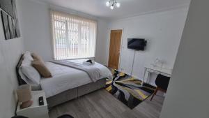 a bedroom with a bed and a desk and a television at Deluxe Double bedroom with private bathroom, parking and WiFi in Leeds