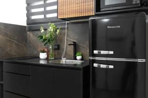 a black kitchen with a sink and a refrigerator at By Eezy - דירת סטודיו מסוגננת במיקום מעולה באילת Ashram 5 in Eilat
