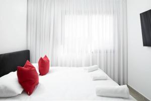 a bedroom with a white bed with red pillows at By Eezy - דירת סטודיו מסוגננת במיקום מעולה באילת Ashram 5 in Eilat