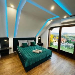 a bedroom with a green bed and a large window at Domki pod Luboniem in Rabka