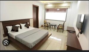 Schlafzimmer mit einem Bett, einem Tisch und einem TV in der Unterkunft Cyber Vista in Gurgaon