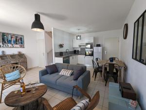 een woonkamer en een keuken met een bank en een tafel bij Maison BARBADINE in Saint-Denis-dʼOléron
