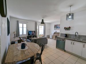 een keuken en een woonkamer met een houten tafel en een eetkamer bij Maison BARBADINE in Saint-Denis-dʼOléron