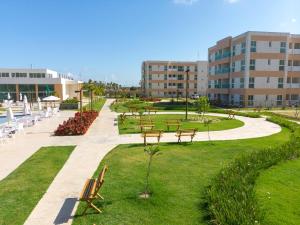 ein Park mit Bänken und Tischen vor einem Gebäude in der Unterkunft Muro Alto Condomínio Clube in Porto De Galinhas