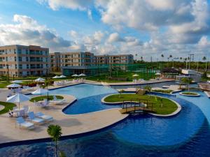 ein Resort mit einem großen Pool mit Stühlen und Sonnenschirmen in der Unterkunft Muro Alto Condomínio Clube in Porto De Galinhas