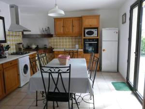 a kitchen with a table with chairs and a white refrigerator at agréable mas au calme jusqu'à 11 pers. près d'Uzès in Saint-Laurent-la-Vernède