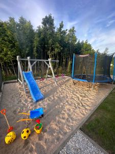 a playground with two swings and a trampoline at Domy wakacyjne WELLE in Kołczewo