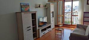 Una sala de estar con un centro de entretenimiento con televisión. en Apartamento Laguna, en Ribadeo