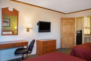 a hotel room with a desk and a television on the wall at Economy Hotel Wichita 2 in Wichita