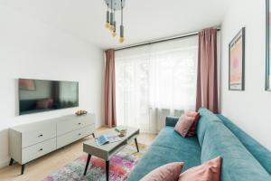 a living room with a blue couch and a tv at Sunset Vibes Apartment in Kołobrzeg