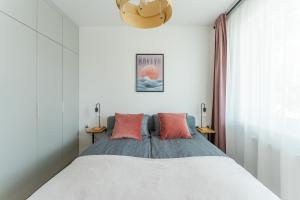 a bedroom with a bed with pink pillows at Sunset Vibes Apartment in Kołobrzeg
