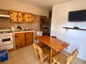 cocina con mesa de madera y TV en la pared en Cabañas Luján, en Potrero de los Funes