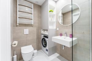 a bathroom with a toilet and a sink and a washing machine at Sunset Vibes Apartment in Kołobrzeg +23 photos