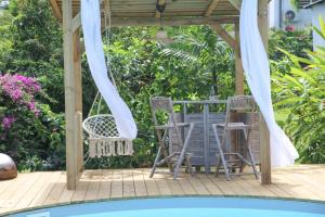 un patio con 2 sillas y un cenador en L Orchidée Bleue, bas de villa, vue mer, piscine privée en Sainte-Anne
